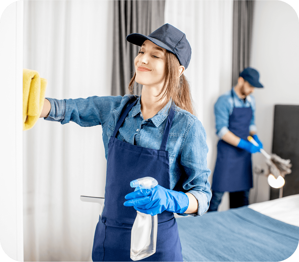 Two women cleaning a room wearing gloves and casual clothes.