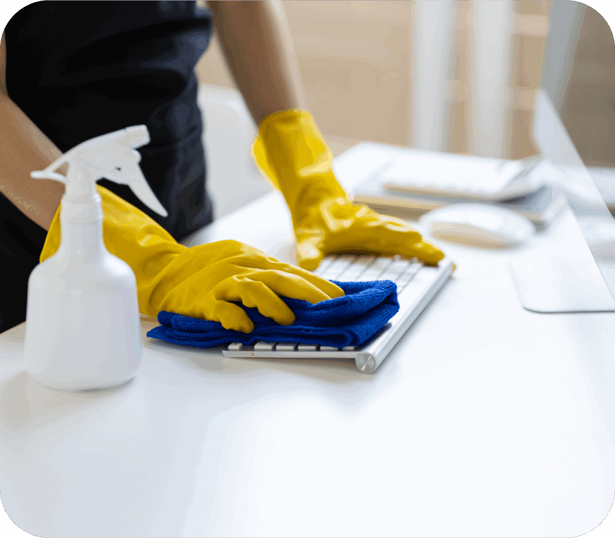 Person cleaning a keyboard with a cloth and wearing yellow gloves.