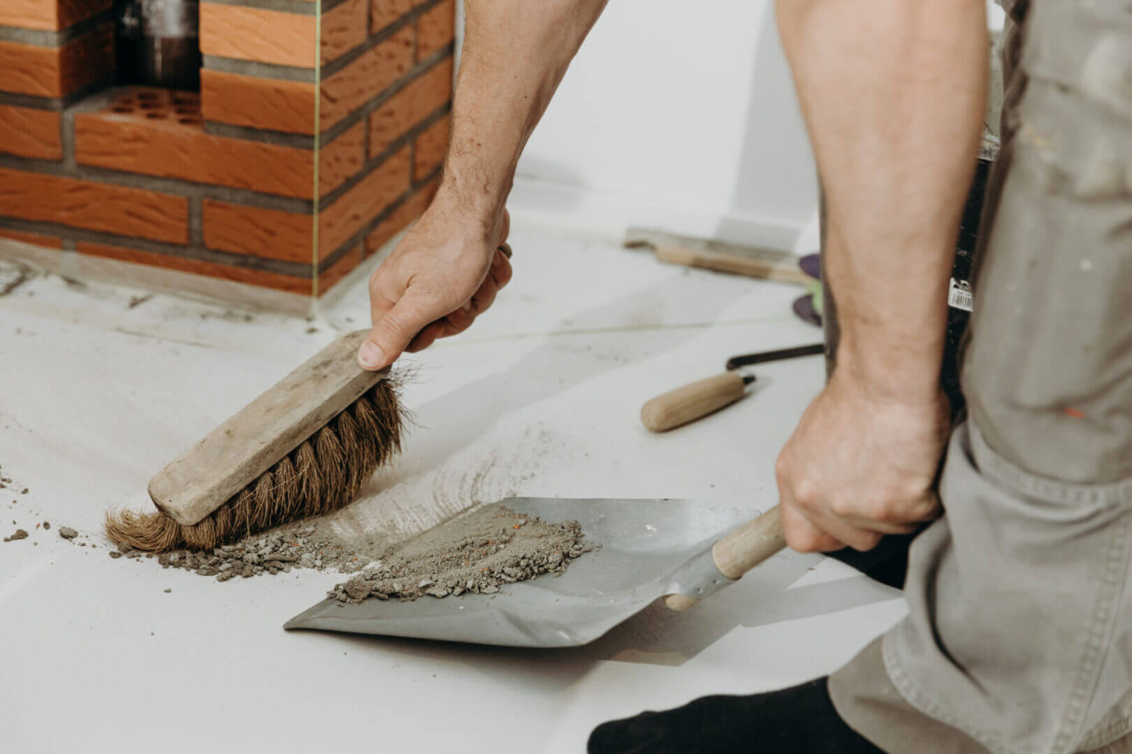 Person sweeping debris into a dustpan on the floor.