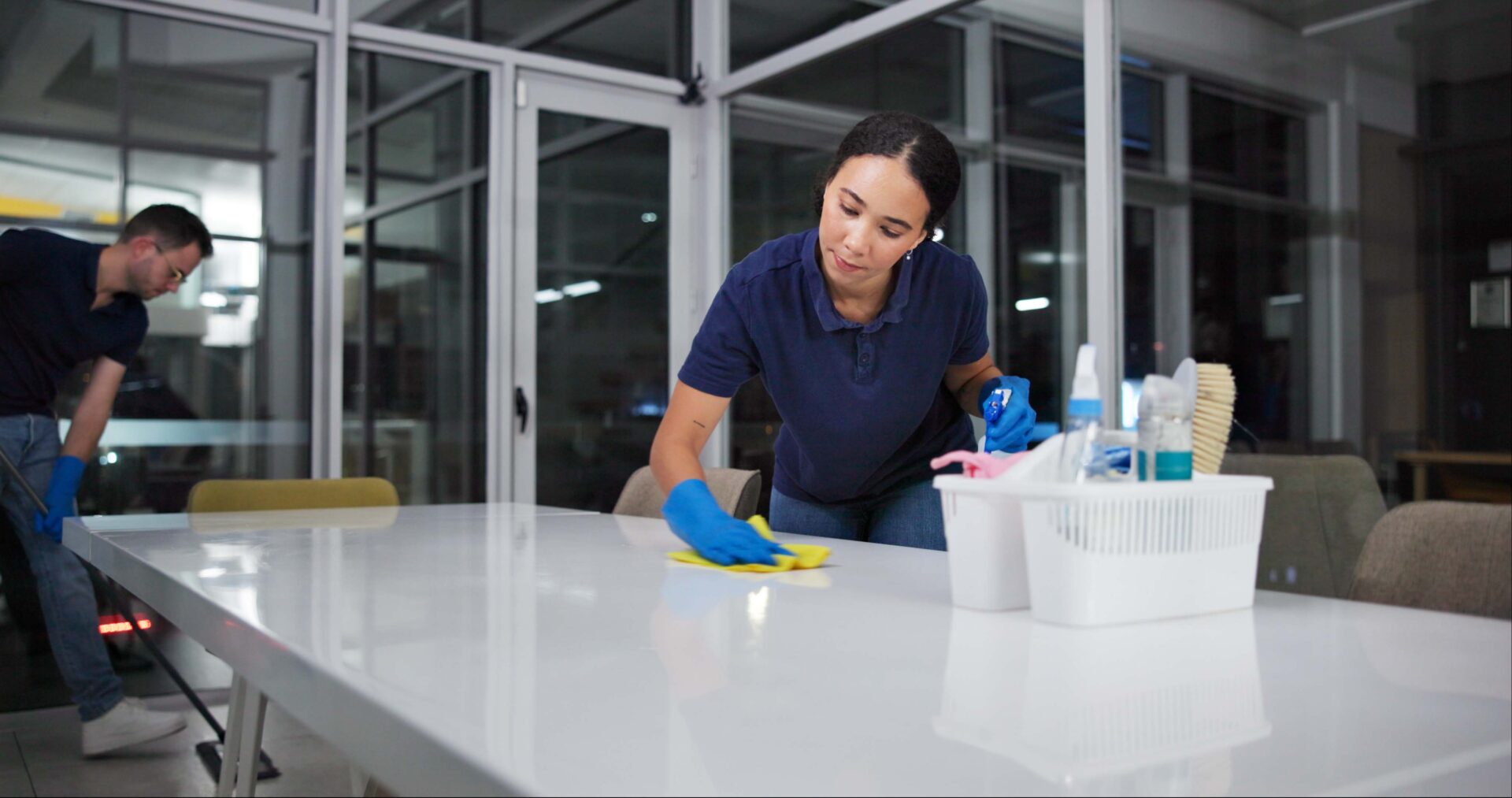 A cleaning professional wipes a counter in a commercial space.