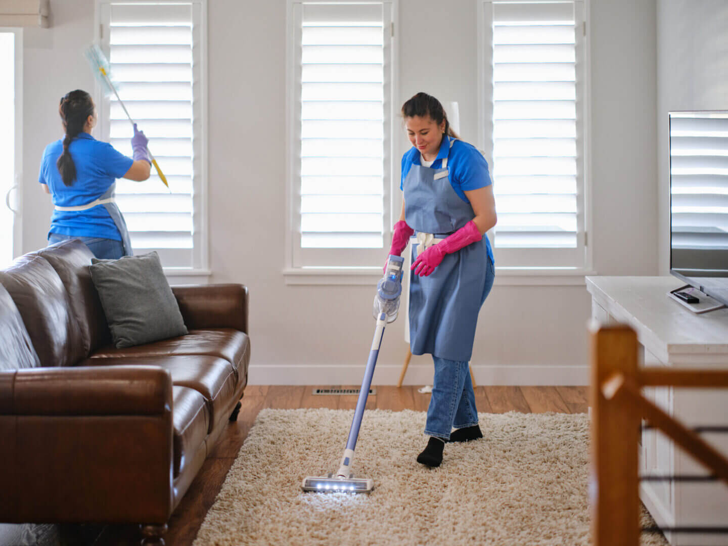 A woman cleaning a carpet with a mop in a bright living room.