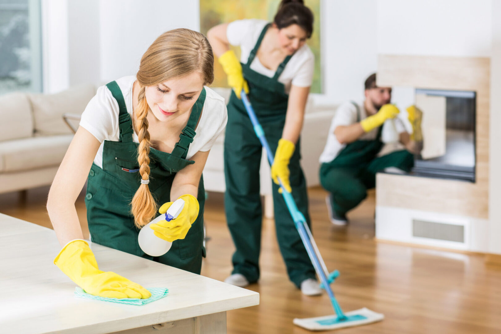 Cleaning staff diligently sanitizing a room with gloves and cleaning tools.